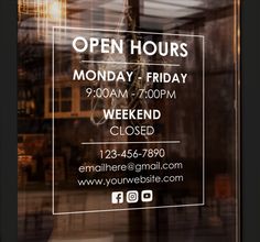 an open hours sign in the window of a store front with lights hanging from it