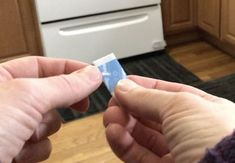 two hands are holding a small card in front of an oven