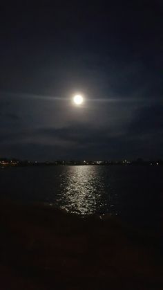 the moon is shining over the water at night