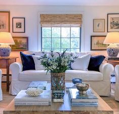 a living room filled with white furniture and lots of pictures on the wall above it