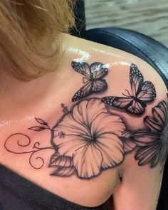 a woman's shoulder with butterflies and flowers on the back of her chest,