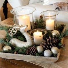 a tray filled with candles and ornaments on top of a wooden table next to a couch