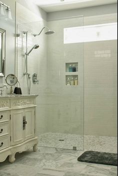 a bathroom with a walk in shower next to a sink and a mirror on the wall