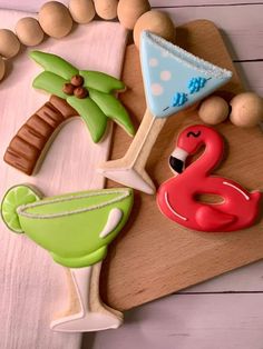 decorated cookies are sitting on a cutting board next to beads and other items that include palm trees