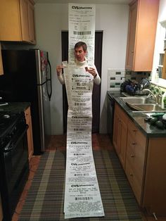 a man standing in a kitchen holding up a large piece of paper with words on it