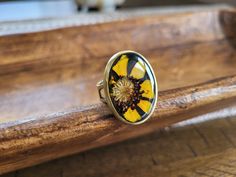 a yellow and black flower ring sitting on top of a wooden bench next to a cat