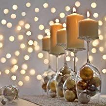 some candles are sitting on a table with ornaments and lights in the backround