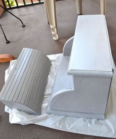 a white bench sitting on top of a piece of plastic next to a wooden chair