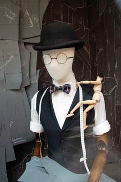 a mannequin wearing a top hat, vest and bow tie with a cane