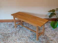 a wooden bench sitting on top of a carpeted floor next to a potted plant