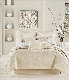 a bed with white comforter and pillows in a room next to vases on the wall