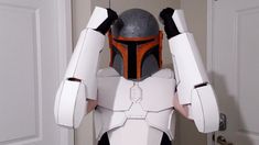 a man in a star wars costume is holding his hands up to his head while standing next to a door