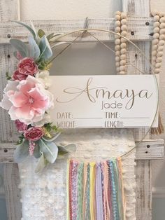 a sign that says amaya jade time, with flowers on it and rainbow ribbons hanging from the front