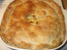 a baked pie sitting on top of a white counter next to a knife and fork