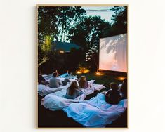 people sitting on blankets watching a movie in the park at night with candles lit up