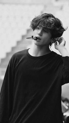 a young man is talking on his cell phone while wearing a nose ring and black t - shirt