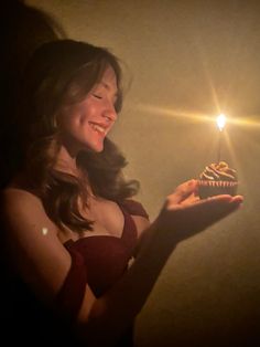 a woman holding a cupcake with a candle in her hand