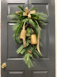 a christmas wreath on the front door with bells and pine cones hanging from it's side