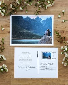 a couple sitting on top of a wooden table next to some flowers and an envelope