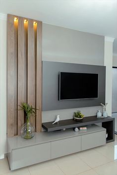 a flat screen tv mounted to the side of a wall next to a vase with flowers