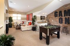 a living room filled with furniture and a foo - pong table in front of a stone wall