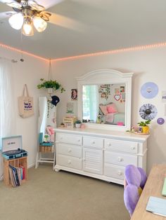 a room with a dresser, mirror and other items on the table in it's corner