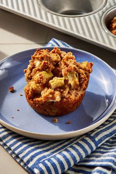 a muffin on a blue plate next to two muffin tins