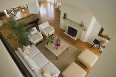 an aerial view of a living room with white couches and fireplace in the center