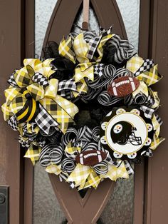 the wreath is decorated with footballs and black and yellow ribbons, which are attached to a door