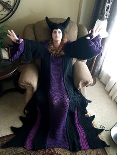 a woman sitting in a chair with her arms spread out and wearing a witches costume