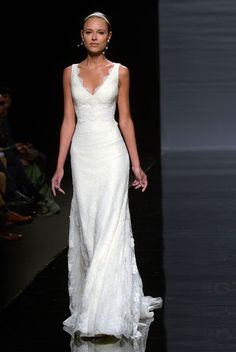 a woman walking down a runway in a white dress