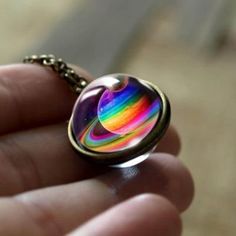 a hand holding a small glass pendant with the words 9 different colors in front of it