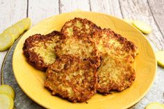 four pancakes on a yellow plate with sliced cucumbers