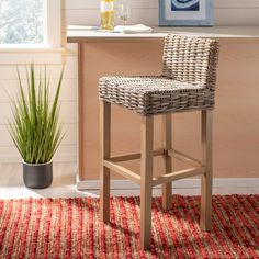 a wicker bar stool sits in front of a counter with a potted plant