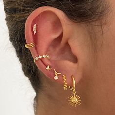 a woman wearing ear piercings with sun and moon designs on the back of her ear