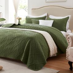 a bed with green bedspread and white pillows