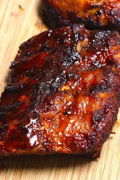 two pieces of bbq ribs sitting on top of a cutting board next to each other