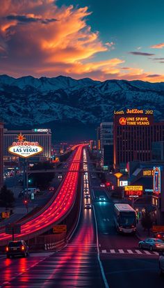 a city street at night with mountains in the background and cars driving on the road