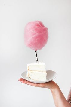 a person holding a piece of cake with a pink ball of yarn on top of it