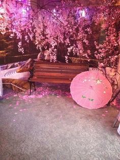 two pink umbrellas sitting on top of a wooden bench under a cherry blossom tree