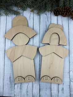 two wooden cutouts sitting on top of a table next to pine cones and evergreen branches