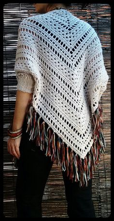 a woman wearing a white crocheted shawl with fringes on the sides