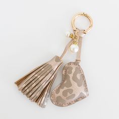 an animal print heart shaped keychain with tassels and a pearl charm