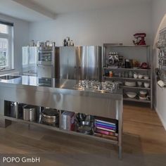 a kitchen with stainless steel appliances and shelves filled with pots, pans, and other items