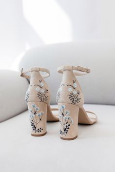 a pair of high heeled shoes with flowers painted on the upper part of them