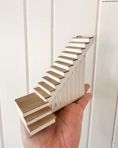 a hand is holding a model of a staircase