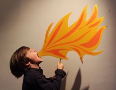 a young boy holding up a yellow and red flame sticker