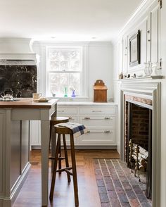 a kitchen with an oven, stove and bar stools in front of the fireplace