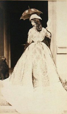 an old black and white photo of a woman in a wedding dress holding an umbrella