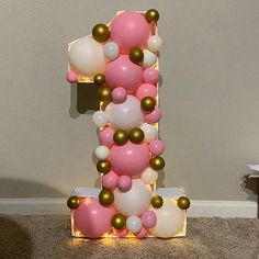 a number one made out of balloons on the floor with a light up sign behind it